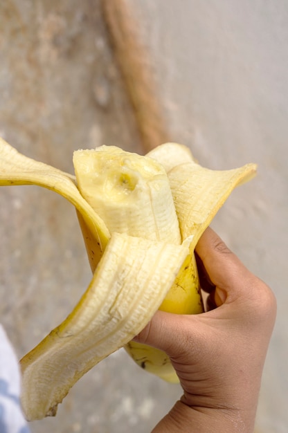 Foto selektiver fokus der kinderhand, die banane hält, banane in der kinderhand