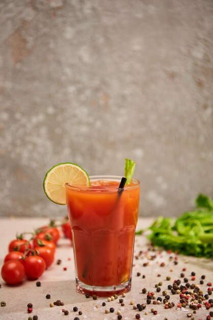 Selektiver Fokus des Bloody-Mary-Cocktails im Glas mit Strohhalm und Limette in der Nähe von Salzpfeffertomaten und