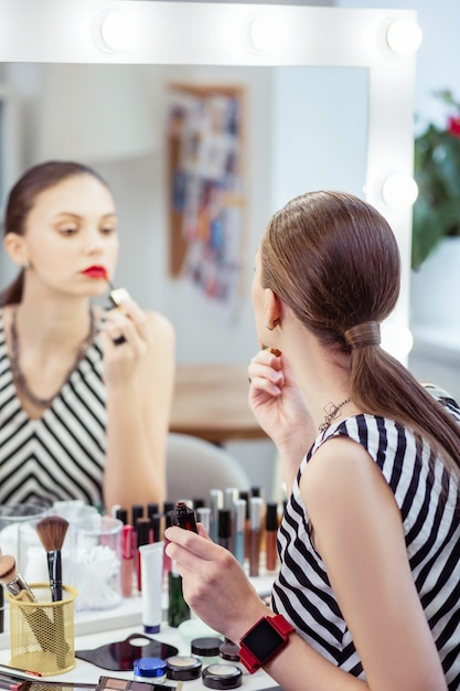 Selektiver Fokus einer schönen jungen Frau, die ihr Spiegelbild im Spiegel betrachtet