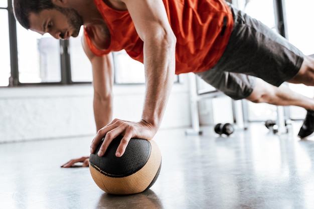 Selektiver Fokus eines gutaussehenden Sportlers, der Plankenübungen mit Ball macht