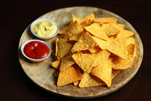 Selektiver Fokus Maischips Nachos mit Saucen auf einem Holzbrett Mexikanischer Snack