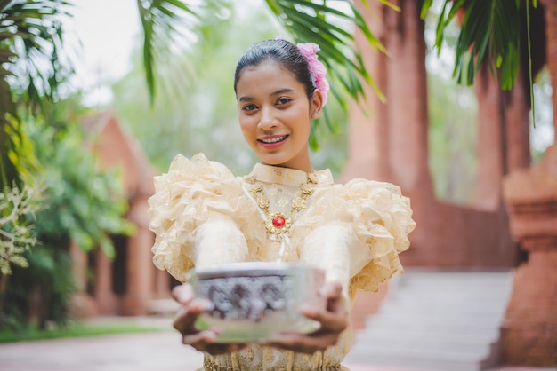 Selektiver Fokus Portrait schöne Frau beim Songkran Festival mit traditioneller thailändischer Tracht im Tempel mit Wasserschale und Lächeln Thailand-Kultur mit Wasserfest