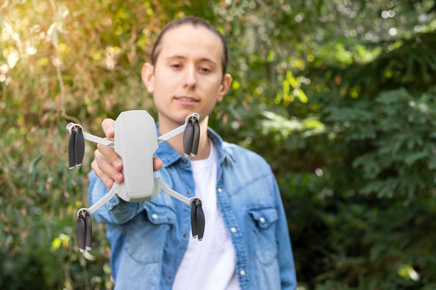 Selektives Fokusporträt einer tragbaren Quadrocopter-Drohne mit 4K-Kamera, die ein kleiner Junge in der Hand hält