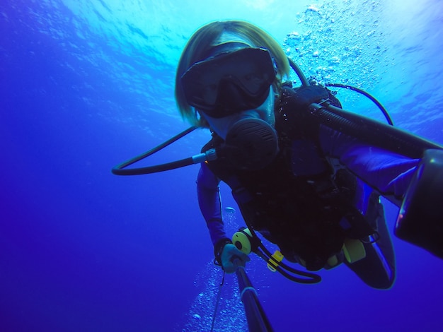 Selfie buceo submarino disparó con selfie stick. profundo mar azul. gran angular disparo.