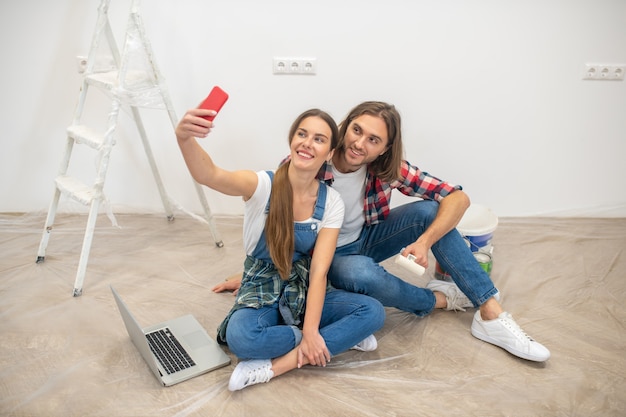 Selfie. Casal feliz sentado no chão fazendo selfie