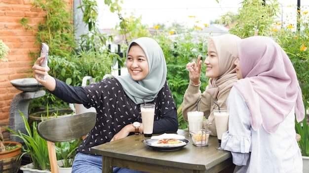 Selfie de grupo de mulher asiática com hijab em um café com uma amiga