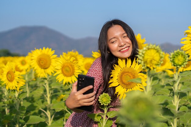 Selfie de jovem feliz com lindo girassol e céu azul