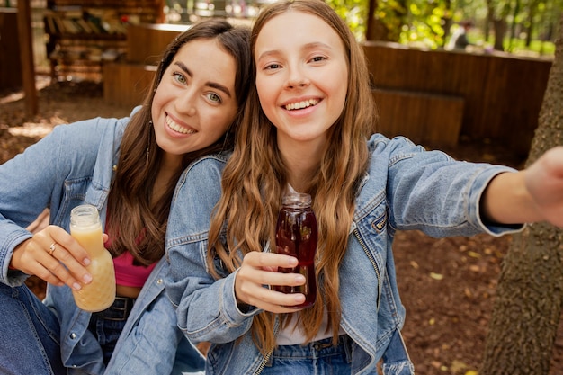 Foto selfie de mulheres jovens segurando garrafas de suco fresco