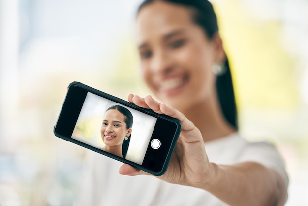 Selfie de telefone e tela com uma mulher tirando uma foto em seu smartphone para mídia social Retrato de rosto e foto na cabeça de uma mulher posando para uma foto usando apenas a tecnologia móvel sem fio