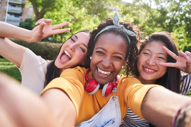 Selfie de três mulheres jovens multiculturais animadas e alegres ao ar livre, mulheres atraentes a divertir-se.