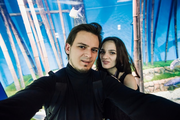 Selfie de um lindo casal, um homem e uma mulher, no fundo de um grande aquário