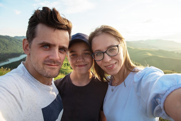 Selfie der Familie in den Bergen glückliche Eltern und glückliches Kinderreisekonzept