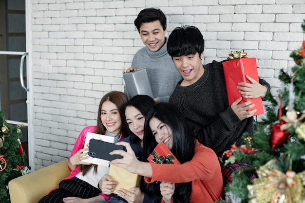 Selfie der Gruppe junger Asiaten mit Geschenken zu Hause beim Feiern des Weihnachtsfestes. Thailändische Teenager feiern Weihnachten und Neujahr. Frohe Weihnachten und schöne Feiertage.