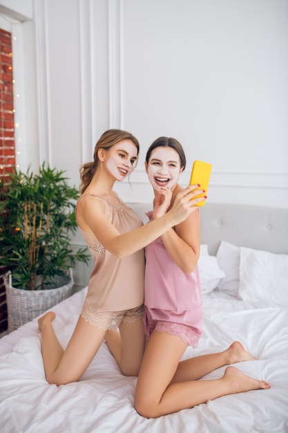 Selfie. Dos chicas lindas con máscaras faciales haciendo selfie