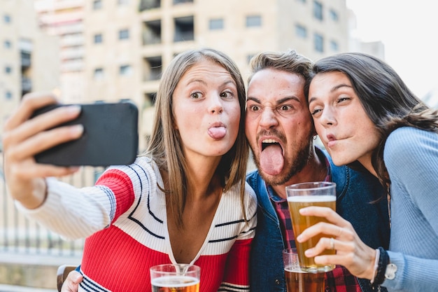 Selfie em grupo de pessoas da geração z fazendo expressão facial engraçada procurando vício em mídia social de smartphone