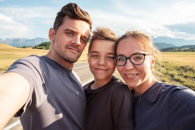 Selfie de familia en la montaña, padres felices y concepto de viaje de niño feliz