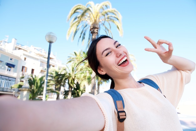 Selfie de feliz diversión mujer con signo de paz sonriendo