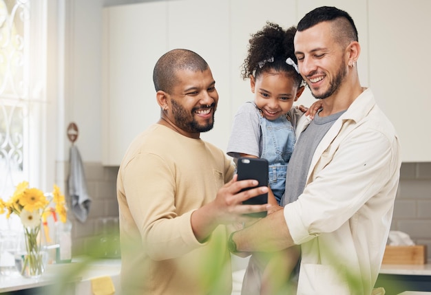 Selfie gemischte Familie und ein Mädchen mit ihren LGBT-Eltern in der Küche zusammen für ein Social-Media-Profilbild Adoptionsfoto Lächeln oder Liebe und eine Tochter mit ihrem schwulen Vater zu Hause