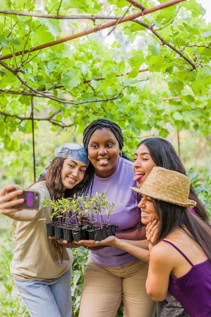 Foto selfie de grupo de voluntarios multiétnicos trabajo en equipo de amistad en jardín urbano mujeres latinas y marroquíes