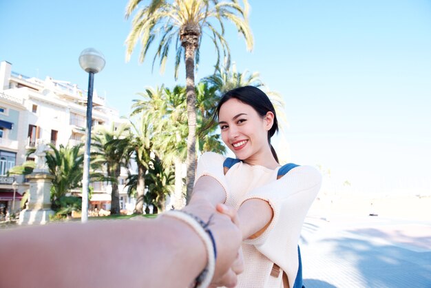 Selfie de hermosa mujer sonriendo y parado afuera por palmeras