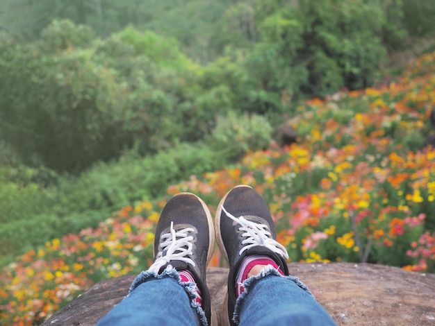 Selfie-Hipster mit schwarzen Turnschuhen über wildem Blumenfeldhintergrund auf dem Berg