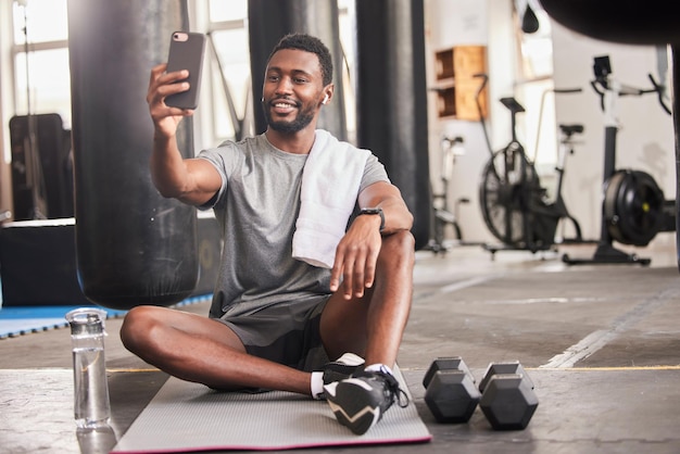 Selfie hombre negro y gimnasio para hacer ejercicio y hacer ejercicio para la conectividad de las redes sociales y relajar al atleta afroamericano y al teléfono inteligente para compartir fotos de fitness y bienestar con una sonrisa