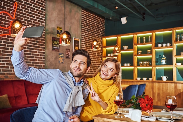 Selfie im teuren Restaurant. Junges Paar lächelt und macht Selfie-Foto am Telefon beim Abendessen