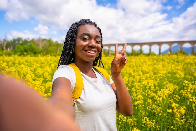 Selfie in der Natur mit einer Vintage-Kamera ein Mädchen schwarzer Ethnizität mit Zöpfen ein Reisender in einem Feld gelber Blumen