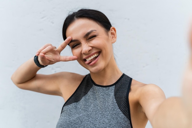 Selfie-Kameraansicht der brünetten glücklichen Frau, die sich vor der Kamera verzieht, während sie ihr Porträt aufnimmt Fröhliches sportliches Mädchen, das sich nach dem Training aufgeregt fühlt