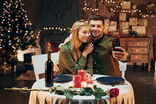 Selfie mit dem Telefon machen Junge schöne Paare haben ein romantisches Abendessen drinnen zusammen