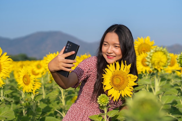 Selfie de niña feliz con hermoso girasol y cielo azul