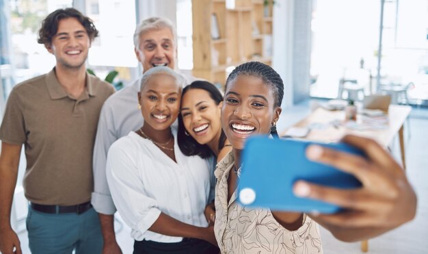 Selfie por telefone e trabalho em equipe com uma equipe de negócios trabalhando em colaboração em seu escritório e tirando uma foto Diversidade de motivação e fotografia com amigos felizes se divertindo juntos no trabalho