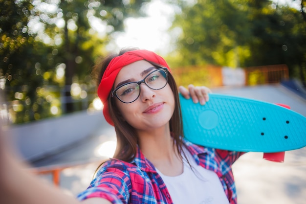 Selfie-Porträt der lustigen jungen Frau in den Gläsern und im roten karierten Hemd.