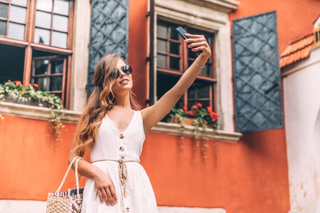 Selfie-Porträt einer jungen Frau auf der Straße mit einem Smartphone