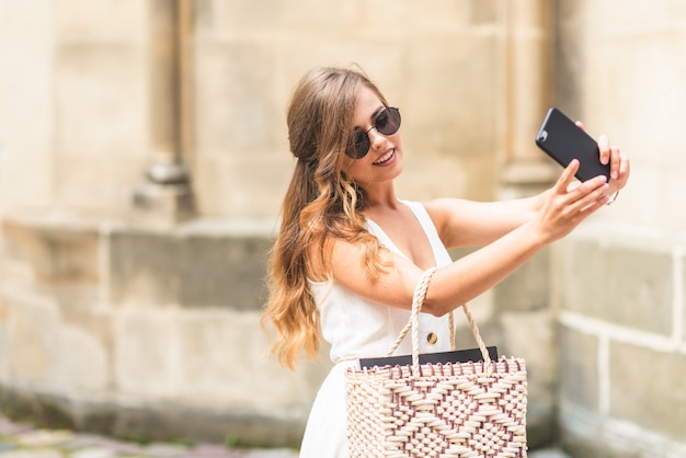 Selfie retrato de uma jovem mulher na rua com um smartphone