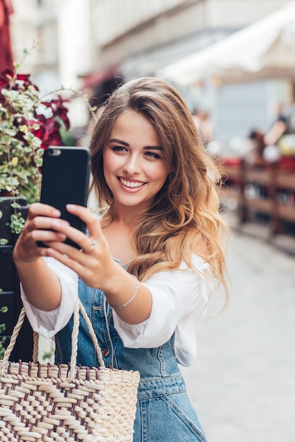 Selfie retrato de uma jovem mulher na rua com um smartphone