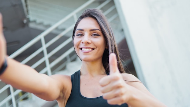 Selfie retrato de una mujer alegre deporte en ropa deportiva al aire libre en el entorno urbano