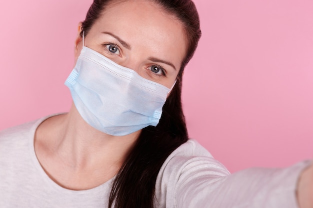 Selfie retrato de una niña morena en una máscara médica.