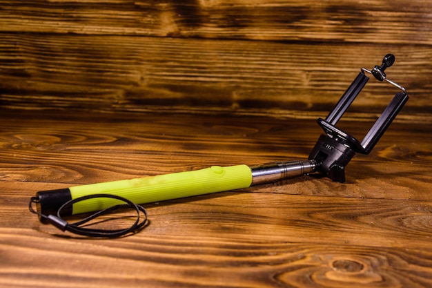 Selfie stick con abrazadera ajustable sobre mesa de madera rústica