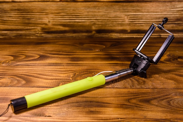 Selfie stick con abrazadera ajustable sobre mesa de madera rústica