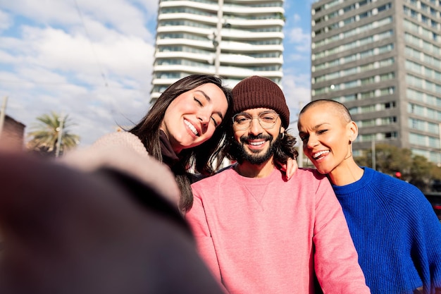 Selfie de tres amigos felices sonriendo en la ciudad