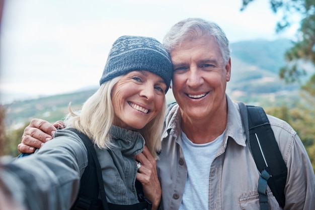 Selfie und Porträt eines alten Paares beim Wandern im Wald und glückliche Menschen in der Natur und Erinnerung für Social-Media-Beiträge. Lächeln im Bild, Abenteuer und Fitness, Mann und Frau mit aktivem Lebensstil und Outdoor