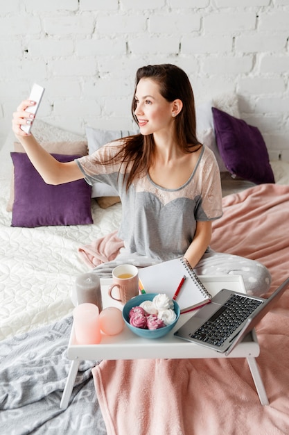 Selfie vom Morgen. Lächelnde schöne Frau macht Selbstporträt mit dem Smartphone.