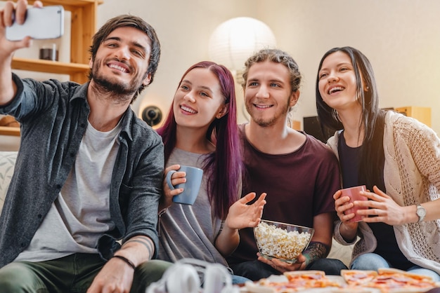 Selfie von glücklichen Freunden, die zu Hause mit Pizza und Kaffee feiern