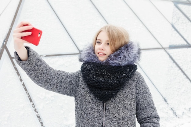 Selfie-Zeit, junge funky Bloggerin macht ein Foto für ihre Social-Network-Seite. Junge glückliche Frau, die selfie nimmt. Kaltes sonniges Wetter. Frau Winterkonzept.