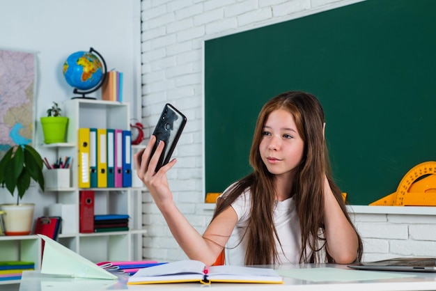 Selfies machen. Mädchen ist College-Studentin. zurück zur Schule. Teenager-Mädchen arbeiten im Klassenzimmer mit Smartphone. fröhliches kind lernt fach online. moderne Bildung. Tag des Wissens. Kinderschüler mit Telefon.