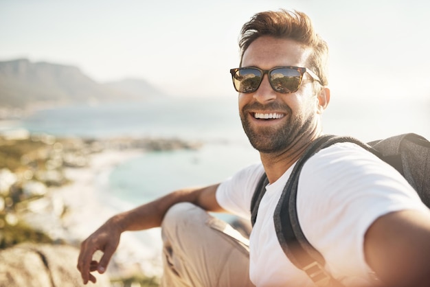 Selfies mit Aussicht Abgeschnittenes Porträt eines hübschen jungen Mannes, der beim Wandern in den Bergen Selfies macht