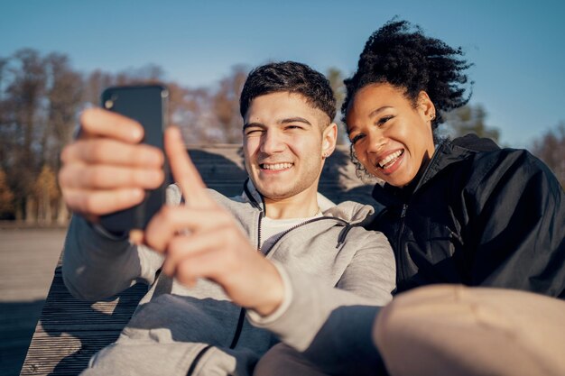 Foto selfies se toman en el teléfono pareja joven caminando en el parque