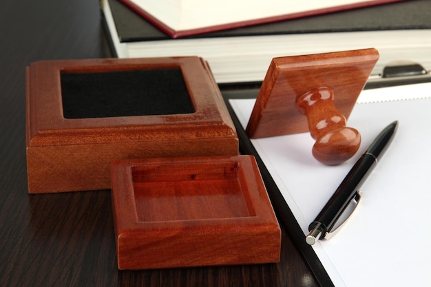 Foto sello de madera con clipboard y libros en la mesa