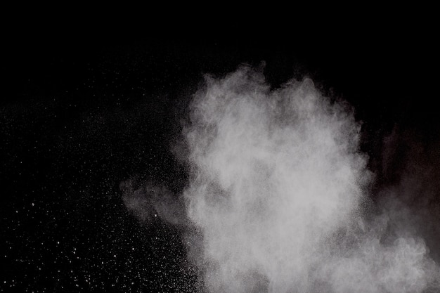Seltsame Formen der weißen Pulverexplosionswolke gegen schwarzen Hintergrund. Weißes Staubpartikelspritzen.